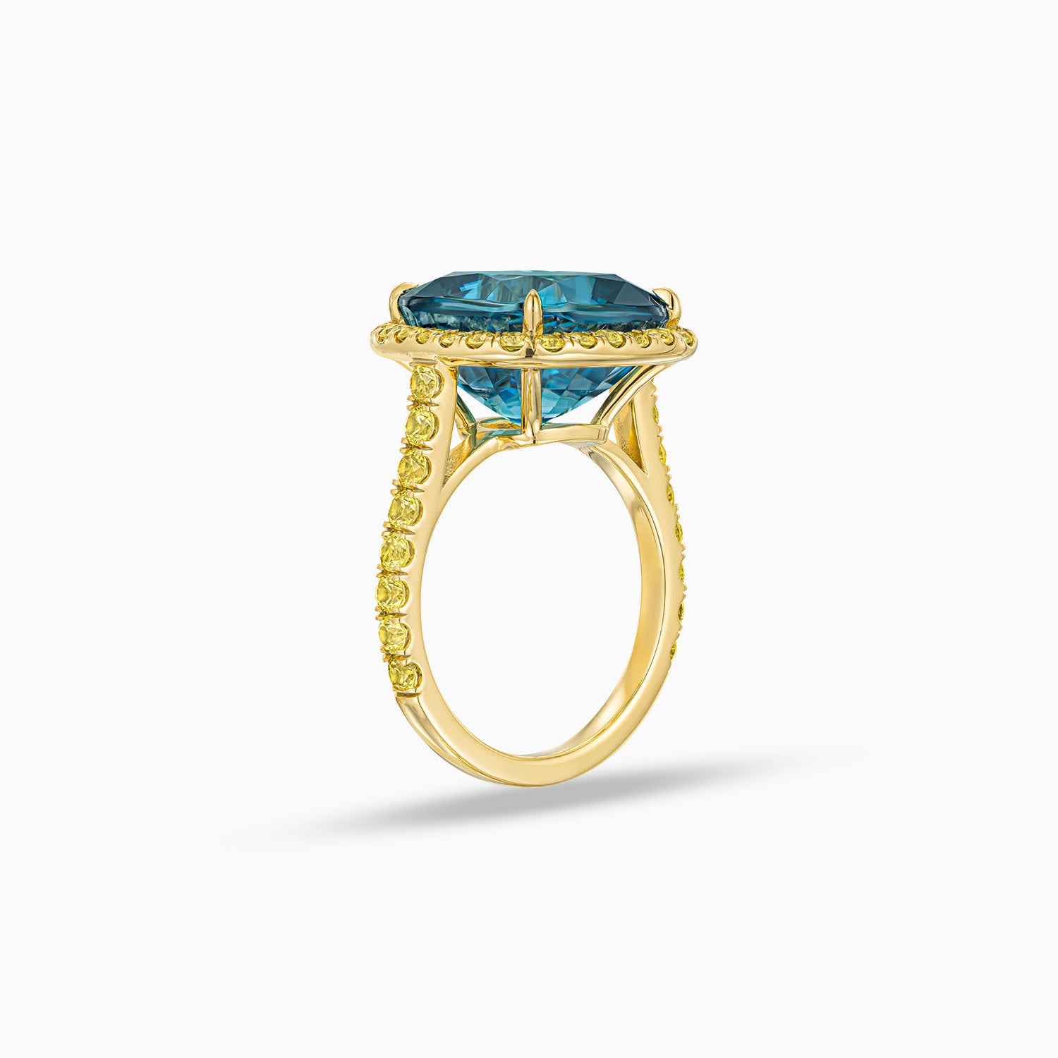 Side view of cushion shape blue zircon ring with yellow sapphire halo in 18K yellow gold