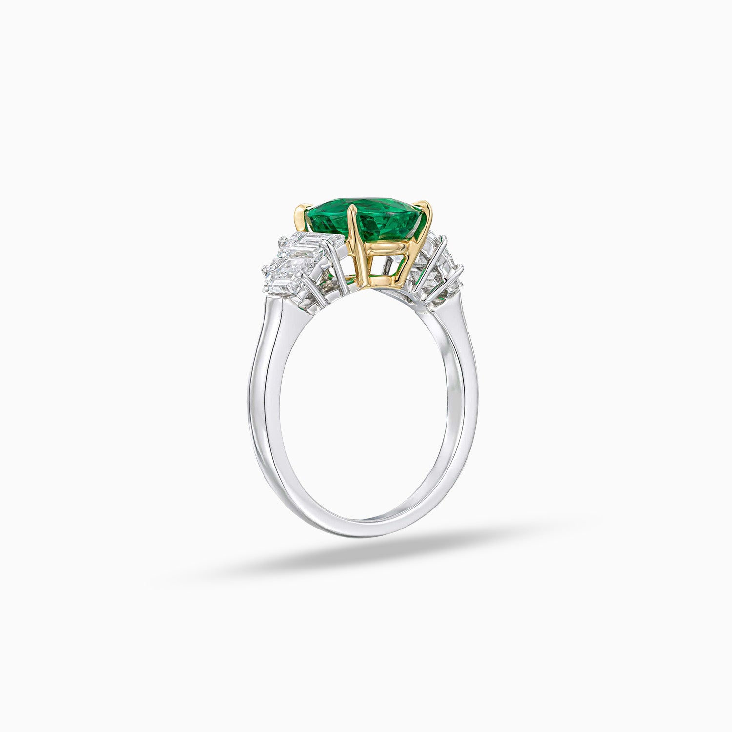 Side view of round Colombian emerald engagement ring with trapezoid diamonds in platinum and 18K yellow gold