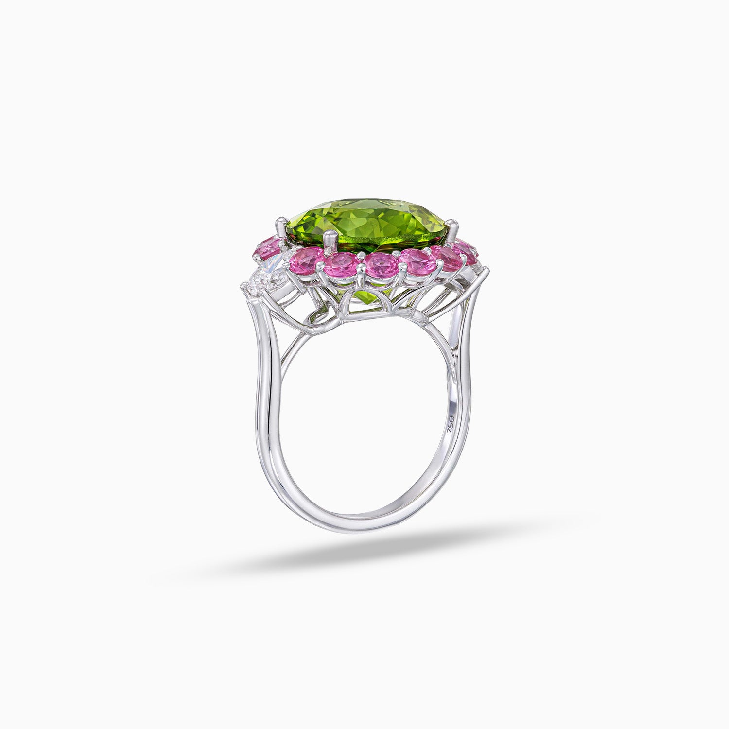 Side view of round peridot ring with pink sapphire halo and pear shape diamond side stones in 18K white gold